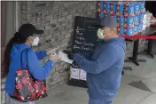  ?? DAMIAN DOVARGANES — THE ASSOCIATED PRESS ?? People buy a box of face masks with a credit card outside Masataco, a taco shop in Whittier on Tuesday. Masataco has managed to sell thousands of face masks at cost, mostly to first responders.