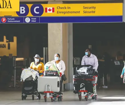  ?? JEFF MCINTOSH / THE CANADIAN PRESS FILES ?? Passengers wear masks at Calgary's airport. It might be up to you to find out if anyone infected with COVID shared your flight, writes John Ivison.