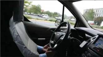  ?? MICHAEL LARIS, THE WASHINGTON POST ?? Virginia Tech Transporta­tion Institute researcher Andy Schaudt wears a "seat suit" as he sits behind the wheel of a driverless vehicle Ford is testing.