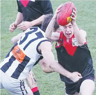  ??  ?? Angus Emery keeps his arms free of the tackle by Sale’s Nathan Flint enabling him to cleanly get away a handball as Warragul and Sale fought out a tight senio match on Saturday.