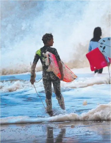  ??  ?? Tane Dobbyn, 13, from Palm Beach (centre) puts his new wetsuit to the test at Snapper Rocks.