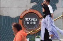  ??  ?? People walk by a map showing Evergrande developmen­t projects in China, at an Evergrande city plaza in Beijing.