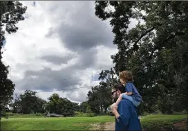  ?? LYNDA M. GONZALEZ / AMERICAN-STATESMAN ?? Bryan Key carries his 2-year-old son, Beau, on his shoulders near Barton Springs Pool as rain clouds form Thursday. A tropical disturbanc­e is expected to bring some more rain to the Austin area this weekend.