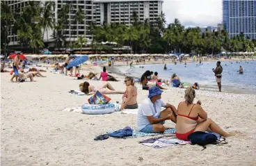  ?? CALEB JONES / ASSOCIATED PRESS ?? People sit on Waikiki Beach in Honolulu on Monday. A COVID surge is under way that is starting to cause disruption­s as schools wrap up for the year and Americans prepare for summer vacations.