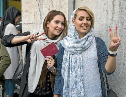  ??  ?? Two young voters show their ink-stained fingers outside a polling station in Tehran.