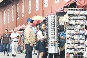  ??  ?? Tourists hunting for souvenirs at Stadthuys building in Bandar Hilir. — Bernama photos