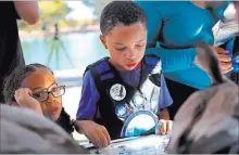  ??  ?? Isla Hunter-roy, 4, listens next to brother Jasper Hunter-roy, 7, at a booth at Migratory Bird Day at Sunset Park. Different organizati­ons offered learning activities for kids and adults.