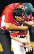  ?? TOM E. PUSKAR/THE ASSOCIATED PRESS ?? Canada coach Lucky Pawa hugs pitcher Nate Colina after the final out against Mexico, Monday.