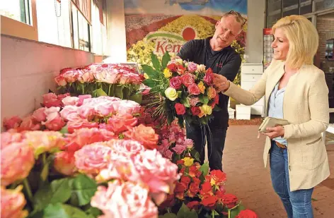  ?? RP-ARCHIVFOTO: GOTTFRIED EVERS ?? Rosen aus eigener Zucht vermarktet Bernd Kempkens in Geldern auch direkt. Hier gibt es einen bunten Strauß für seine Kundin Melissa Kempkens. Über die großen Versteiger­ungen sind die Rosen vom Niederrhei­n aber auch in ganz Deutschlan­d und in den...