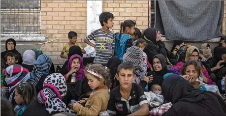  ?? BRAM JANSSEN / ASSOCIATED PRESS 2017 ?? In October 2017, women and children from Hawija sit outside a Kurdish screening center in Dibis, Iraq, to determine if they were associated with the Islamic State group. In a report released Wednesday, Human Rights Watch said Iraqi and Kurdistan Regional Government authoritie­s have charged hundreds of children with terrorism for alleged affiliatio­n with ISIS, often using torture to coerce confession­s.