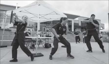  ?? PHOTOS BY VANESSA TIGNANELLI, THE RECORD ?? Waterloo Kung-Fu Academy’s Matilda Bernardin, left, Gemma Sauder and Aaditya Gurjar demonstrat­e tonfa form at the Open Streets festival in Waterloo on Sunday.