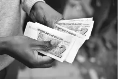  ??  ?? A man holds bond notes released by the Reserve Bank Of Zimbabwe in Harare central business centre. Zimbabwe issues ‘bond notes’ equivalent to the US dollar to ease critical cash shortages, the central bank announced despite widespread public fear of a...