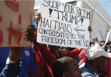  ?? JOE RAEDLE/GETTY IMAGES ?? People gather near Mar-a-Lago resort to condemn U.S. President Donald Trump’s reported statement about immigrants from Haiti and certain African countries and to ask that he apologize to them on Monday in West Palm Beach, Fla.