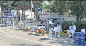  ?? REUTERS ?? Workers in protective suits sit outside a residentia­l compound, following confirmed cases of Covid, in Beijing.