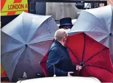 ??  ?? Transfer: Staff hold umbrellas as Philip leaves at back of hospital and, below, police clear path for ambulance
