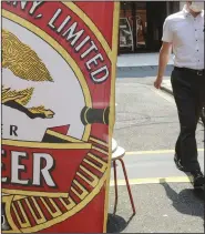  ?? (AP/Koji Sasahara) ?? A man walks near an advertisem­ent of a Kirin brand beer in Tokyo in August 2020.