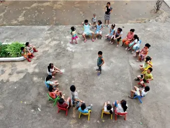  ??  ?? Des enfants jouent sous la conduite d’une enseignant­e, dans la « maison d’amour » du village de Donglushi.