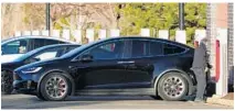  ?? DAVID ZALUBOWSKI/AP ?? A motorist plugs in his Tesla Model X at a supercharg­ing station in the parking lot of an outlet mall on Friday in Lakewood, Colorado.