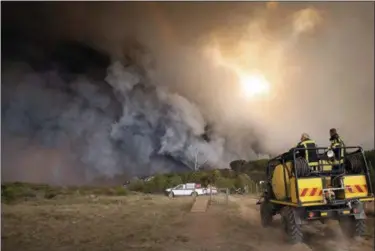  ?? EWALD STANDER — THE ASSOCIATED PRESS ?? In this photo taken Wednesday firemen fight a blaze in the Kranshoek area in South Africa. Fires fanned by high winds have swept through a scenic coastal town in South Africa, killing several people, destroying homes and forcing the evacuation of up to...