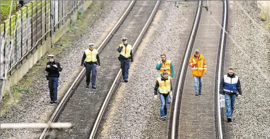  ?? DPA-BILD: GOLLNOW ?? Polizisten und Notfallman­ager der Bahn suchen nahe der Unglücksst­elle die Gleise ab.