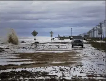  ?? MICHAEL CIAGLO — HOUSTON CHRONICLE VIA AP ?? Vehicles navigate past waves and debris washing over State Highway 87 as Tropical Storm Cindy approaches Wednesday in High Island, Texas.