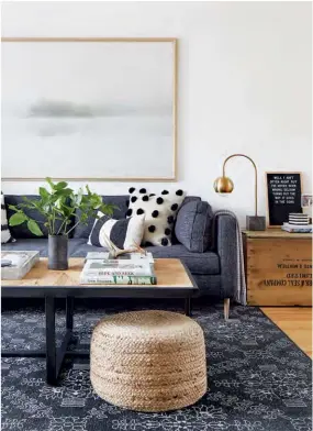  ??  ?? ABOVE A natural compositio­n quietly pays homage to the outdoors: The wooden coffee table, antique crate and jute pouffe bring in natural elements; the rug and toss cushions introduce hits of graphite and stone hues; and the print above the sofa...