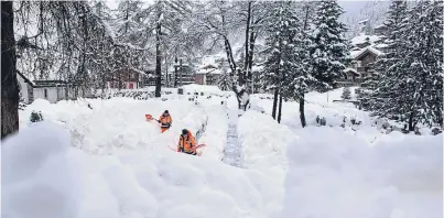  ?? Pictures: AP. ?? Clockwise from top: community workers remove snow off a path in Zermatt, Switzerlan­d; snow covers houses and mountains; support staff handle tourists’ luggage at the Air Zermatt heliport.