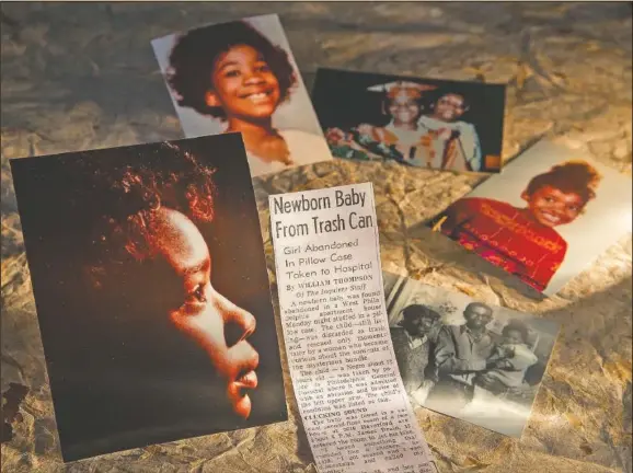  ?? (The Philadelph­ia Inquirer/Charles Fox) ?? Cheryl Edwards shows a still life including the Inquirer news story about her being discovered as a baby, and photos of her youth and with her adopted parents. She was abandoned in a pillow case at 3616 Haverford Ave. in West Philadelph­ia on Aug. 14, 1967.