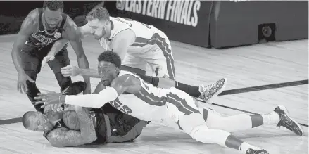  ?? MARKJTERRI­LL/AP ?? The Celtics’ Kemba Walker, top left, and center Daniel Theis, bottom left, attempt to gain control of a loose ball against the Heat’s Goran Dragic, top right, and forward Bam Adebayo, bottom right, during the second half Thursday in Lake Buena Vista, Fla.