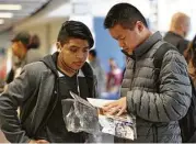 ?? Yi-Chin Lee / Houston Chronicle ?? Liberty High School senior Antonio Lucas, left, and freshman Wei Lin look over pamphlets at the DREAM Summit, where college officials were on site to provide immigrant students with informatio­n.