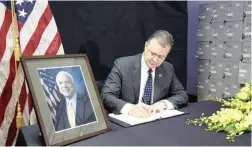  ?? PICTURE: AP ?? WAR TIME: US Ambassador to Vietnam Daniel Kritenbrin­k writes a book of condolence­s for Senator John McCain in Hanoi, Vietnam, yesterday. People in Vietnam are paying respect to McCain who was held there as a prisoner of war.