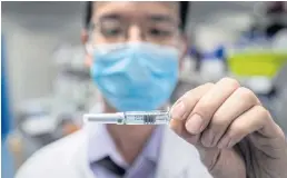  ??  ?? An engineer examines a syringe containing an experiment­al Covid-19 vaccine at the Sinovac Biotech facilities in Beijing. The firm is conducting one of the four clinical trials authorised in China.