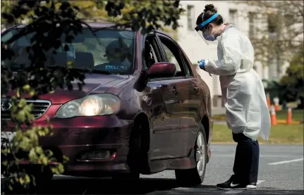  ?? ANDREW HARNIK — THE ASSOCIATED PRESS ?? A medical worker prepares to test a young man for COVID-19at a Children’s National Hospital drive-in testing site at Trinity University on Thursday in Washington.