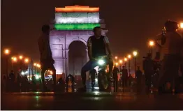  ?? — PTI ?? People walk near India Gate, lit in national tricolours, on the eve of Independen­ce Day in New Delhi on Tuesday.