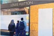  ?? DANIELLE ECHEVERRIA/SAN FRANCISCO CHRONICLE VIA AP ?? Union Square visitors look at damage to the Louis Vuitton store after looters ransacked high-end businesses in San Francisco on Sunday.