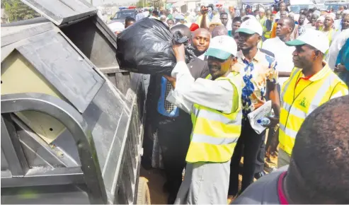  ?? FCT Minister, Malam Muhammad Musa Bello, disposes garbage into one of the mobile refuse collectors in Kwali Area Council, during the flag-off of FCT Household and community sanitation exercise in the Council on Saturday. ??