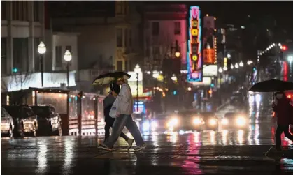  ?? ?? People across the street on Broadway during heavy rain in San Francisco on Sunday. Photograph: Anadolu/Getty Images