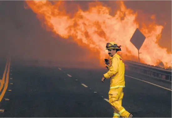  ?? Picture / AP ?? California­n firefighte­rs cleared traffic after the fire forced the shutdown of a section of Interstate 15.