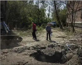  ?? IVOR PRICKETT — THE NEW YORK TIMES ?? Local residents stand on Tuesday near the crater left by an overnight Russian missile strike on an apartment complex in Sloviansk in eastern Ukraine.
