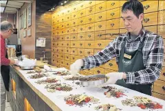  ??  ?? A specialist dispenses herbs at the Kamwo store in New York City.