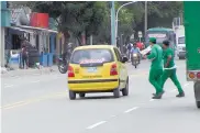  ??  ?? Trabajador­es de una empresa de mensajería atraviesan la calle en medio del tráfico de la zona.