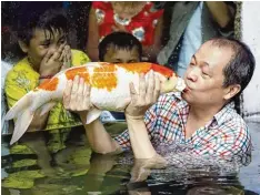  ?? Foto: Dennis M. Sabangan, dpa ?? Ein Küsschen für den Karpfen: Der Koi gilt in vielen Ländern Asiens als Symbol der Stärke.