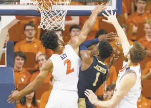  ?? STEVE HELBER/ASSOCIATED PRESS ?? Pittsburgh guard Xavier Johnson tries to go up for a shot as Virginia guard Braxton Key and forward Jay Huff, right, defend during the second half of the No. 2 Cavaliers’ 73-49 victory over the Panthers.