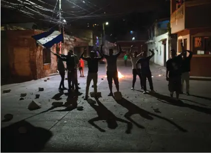  ??  ?? Anti-government protesters shout slogans during a government imposed dusk-to-dawn curfew as they protest purported election fraud in Tegucigalp­a, Honduras. Security forces have shot and killed demonstrat­ors protesting a disputed presidenti­al election...