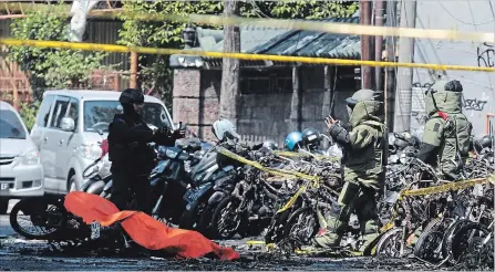  ?? TRISNADI THE ASSOCIATED PRESS ?? Members of a police bomb squad inspect the wreckage of motorcycle­s at the site where an explosion went off outside a church in Indonesia, Sunday.