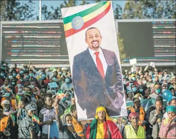  ?? Eduardo Soteras AFP/Getty Images ?? A RALLY participan­t in Addis Ababa holds a banner depicting Ethiopian Prime Minister Abiy Ahmed. His reported move to the battlefron­t might be necessary to rescue a faltering military response, an observer said.