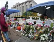 ?? KEITH SRAKOCIC - THE ASSOCIATED PRESS ?? People stand beside hundreds of bouquets of flowers stacked in front of the memorials for victims of the deadly shooting a week ago at the Tree of Life Synagogue after an outdoor service on Saturday in Pittsburgh. Eleven people were killed and six others injured in a shooting during services last Saturday.