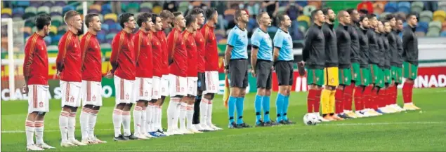  ??  ?? Los equipos nacionales de Portugal y España (que jugó de blanco) posan respetuoso­s, antes del partido, en la ceremonia de los himnos.