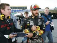  ?? COLIN E. BRALEY — THE ASSOCIATED PRESS ?? Martin Truex Jr. ,center, signs autographs winning the pole for Sunday’s NASCAR Cup Series auto race at Kansas Speedway in Kansas City, Kan., Friday.