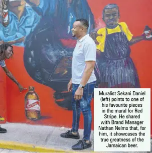  ?? ?? Muralist Sekani Daniel (left) points to one of his favourite pieces in the mural for Red Stripe. He shared with Brand Manager Nathan Nelms that, for him, it showcases the true greatness of the Jamaican beer.